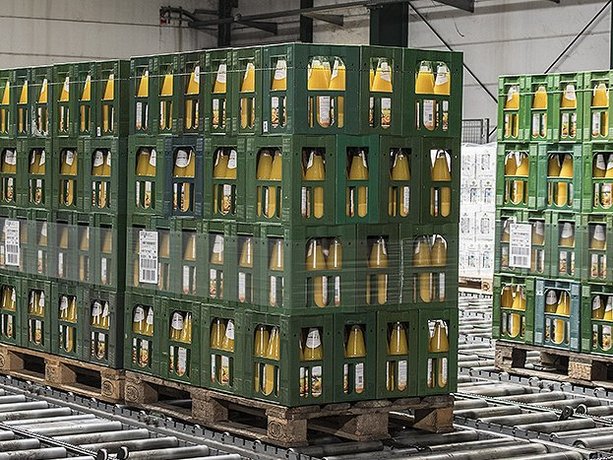 Aufgereihte schwere Ladeeinheiten mit Getränkekisten auf Palette in einem automatischen Fördersystem, beckers bester GmbH