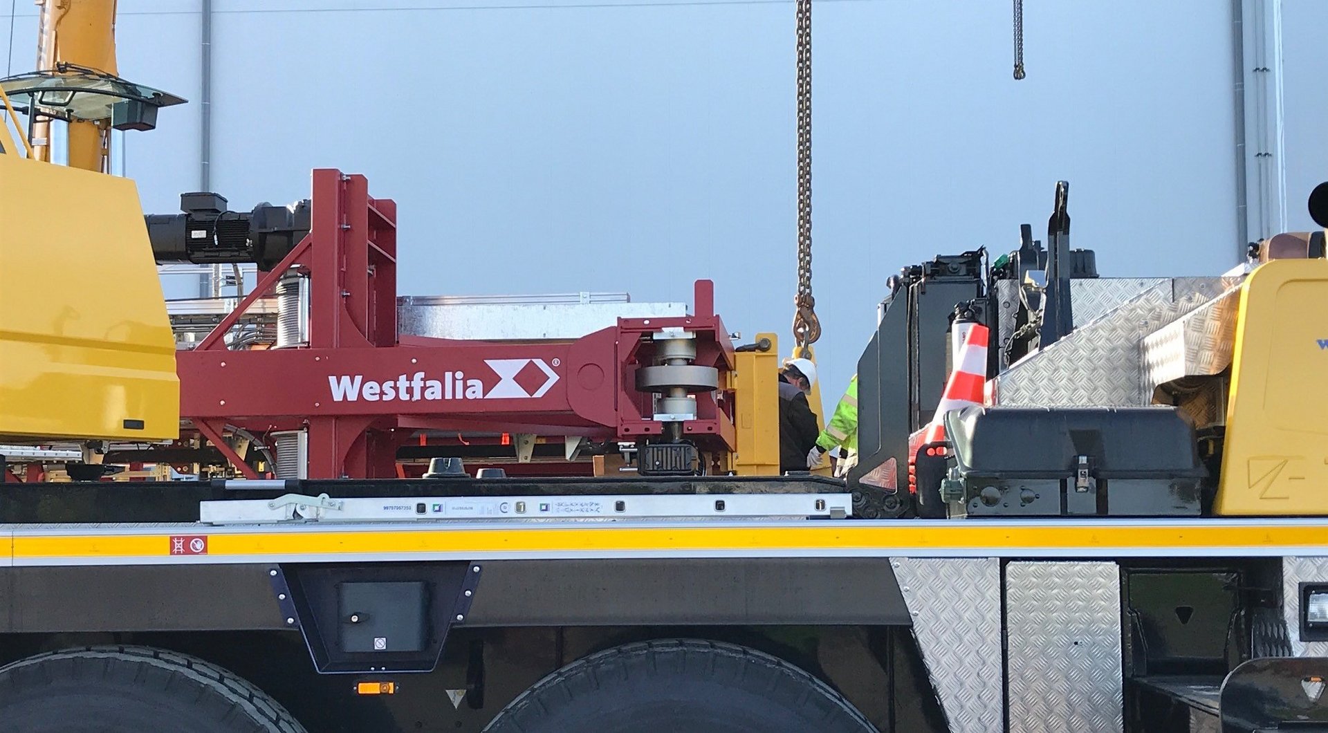 A crane lifts a storage and retrieval machine with the Westfalia logo for a fully automated cold storage facility in Lelystad, Lineage Logistics